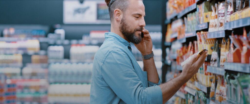 Mann im Laden vor Regalen schaut sich Produkte an