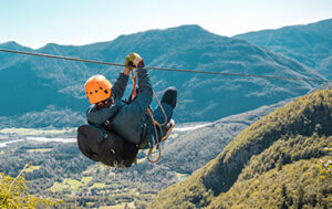 Mann beim Zipline fahren in den Bergen.