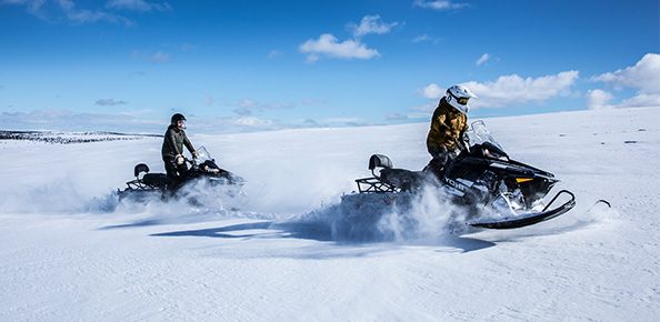 Zwei Personen in Schneelandschaft auf Schneemobilen