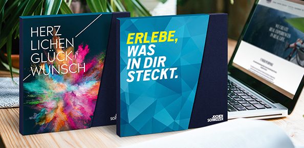 Geschenkverpackungen von Jochen Schweizer mit den Schriftzügen "Herzlichen Glückwunsch" und "Erlebe was in dir steckt."