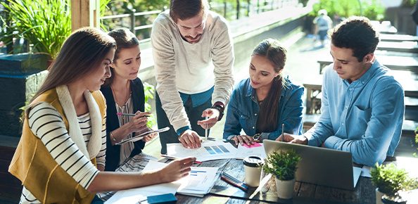 Personen die draußen an einem Tisch sitzen und ein Geschäftsmeeting abhalten