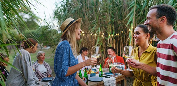 Personen draußen die sich unterhalten und Wein trinken